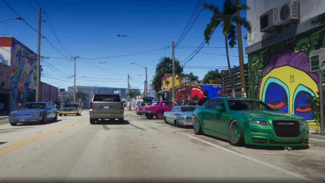 Câmera em um veículo mostra uma rua durante o dia, com carros rebaixados e prédios com paredes cobertas por ilustrações.